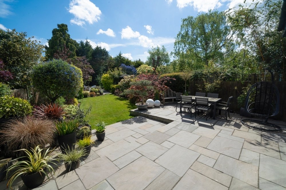 Royale zomertuin in Engelse stijl met uitgestrekt gazon, kleurrijke borders en een ontspannen zomersfeer.